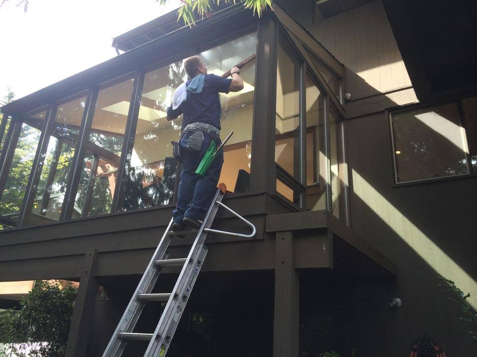 Window cleaning technician on a tall ladder at a Campbell home